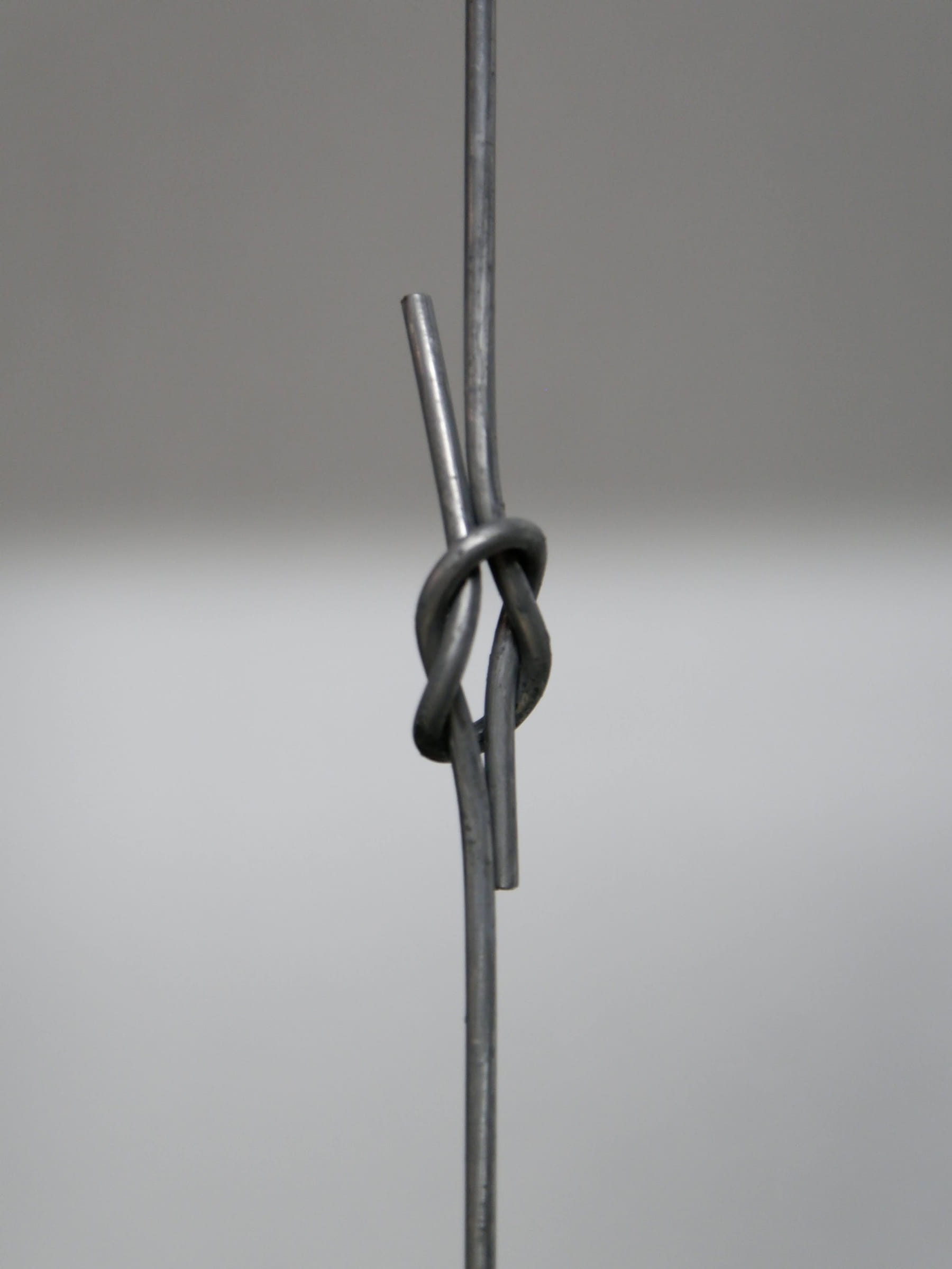Baling wire knotted in an overhand loop against a neutral background
