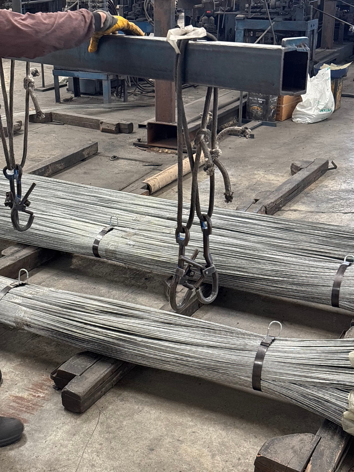 Bundles of straight wire being moved with a lifting clamp in the workshop