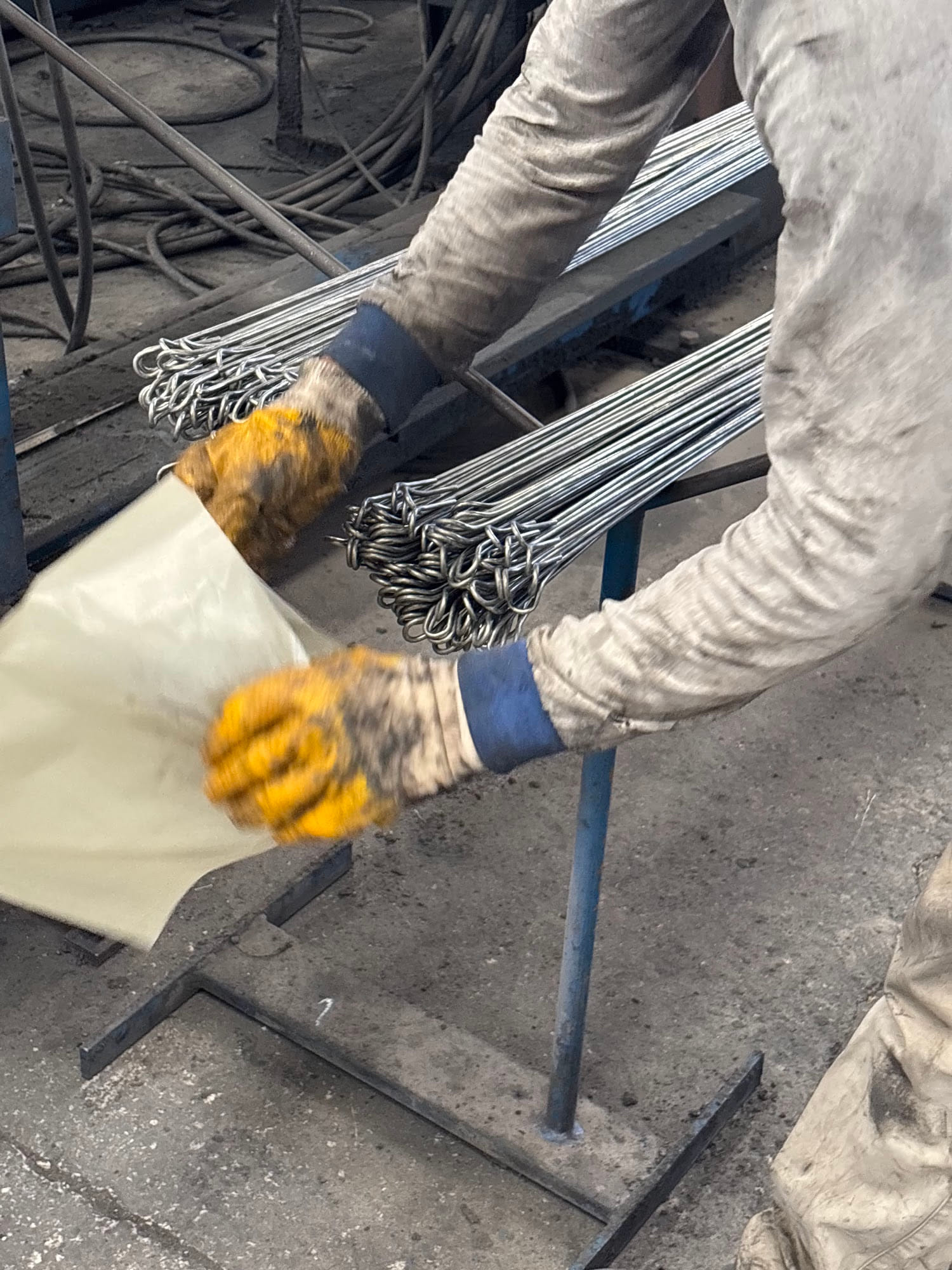 Worker packing two bundles of double loop bale ties into a woven bag