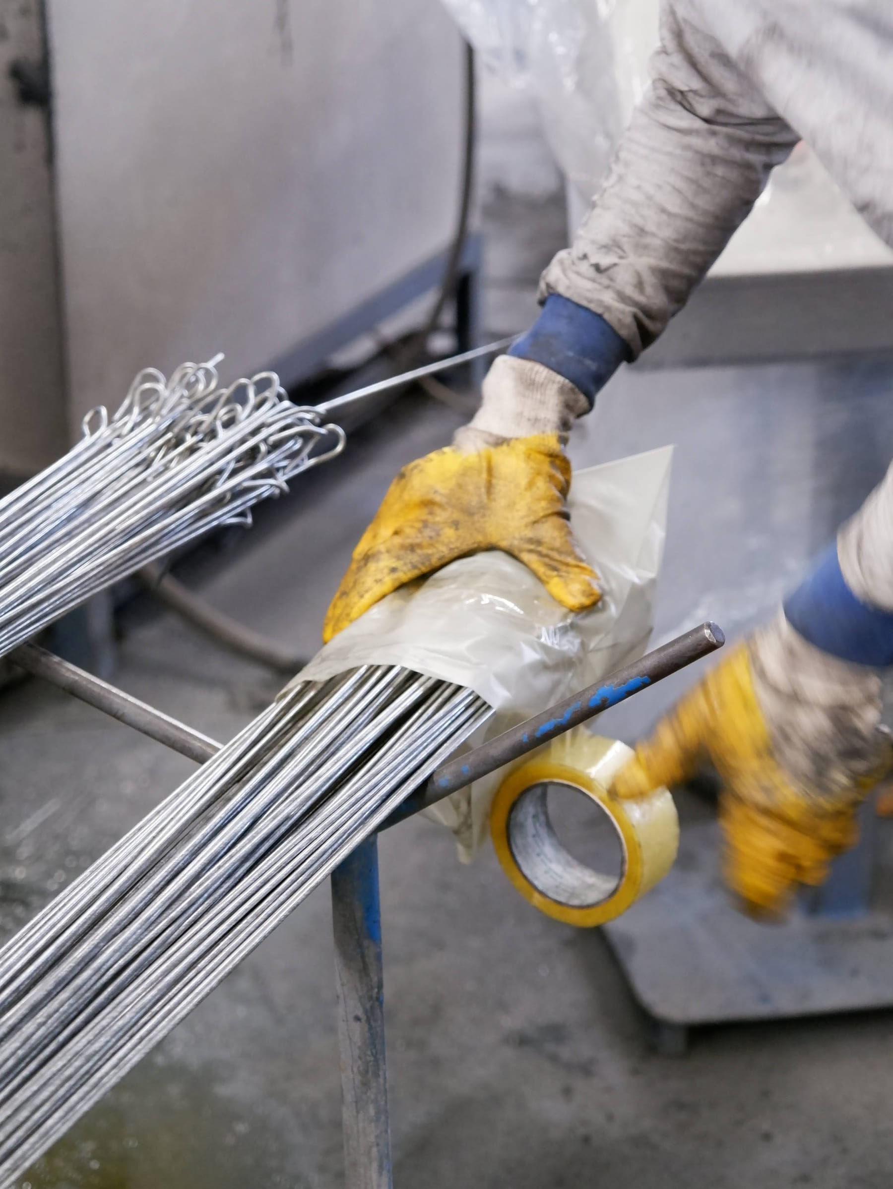 Worker taping a bundle of straight wire with looped ends in the workshop