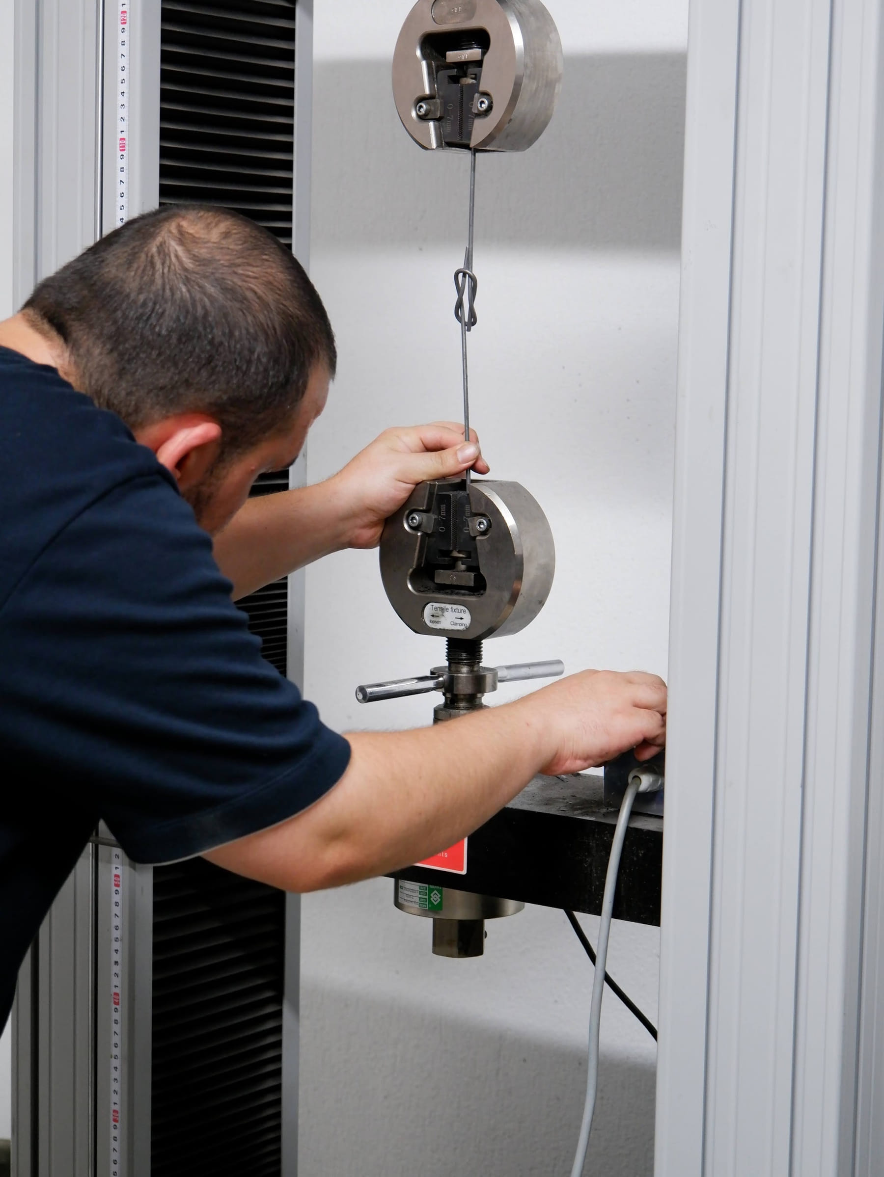 Technician running a tensile strength test on baling wire in a QC lab