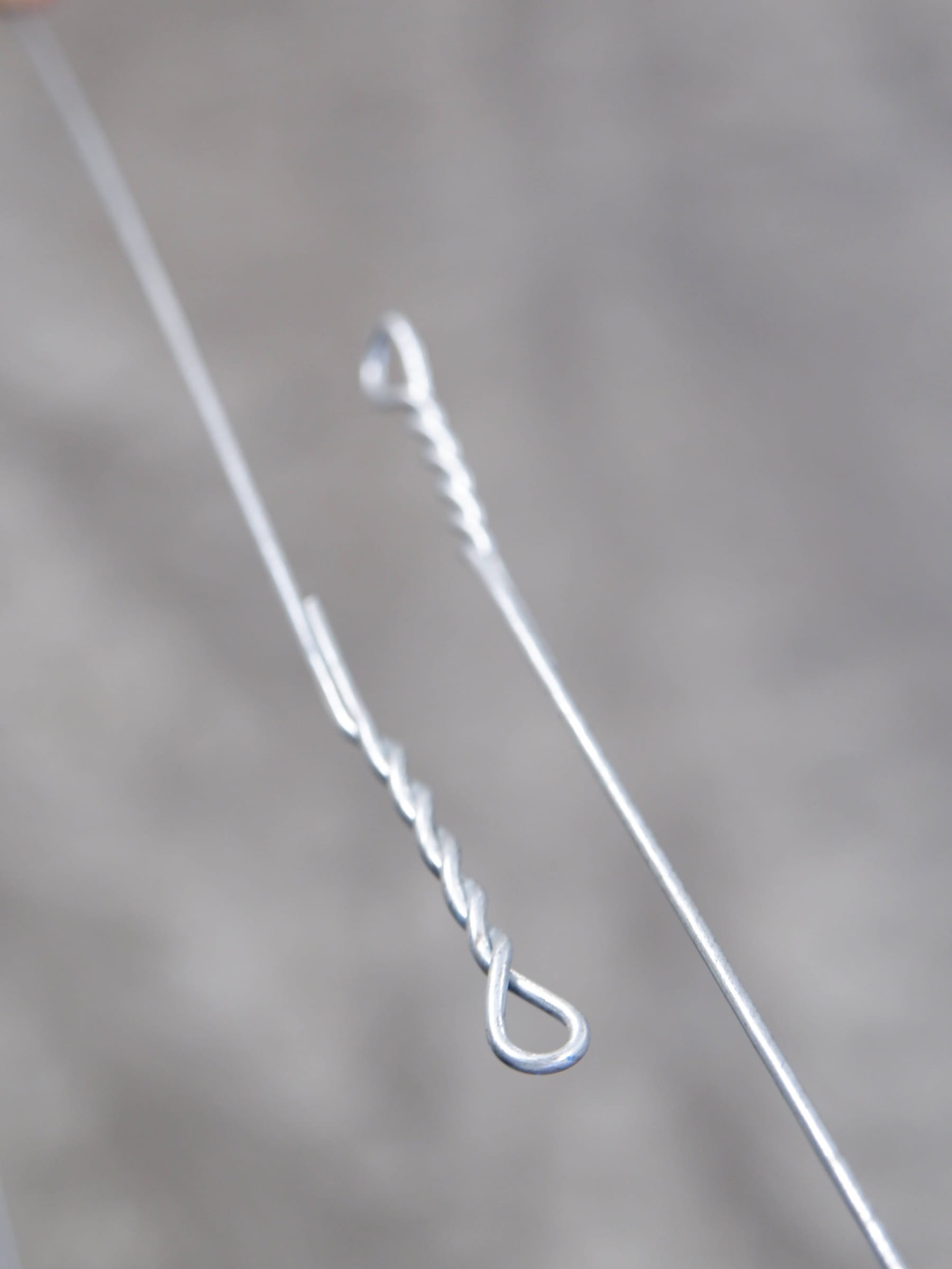 Studio image of a single loop bale tie against a neutral grey background